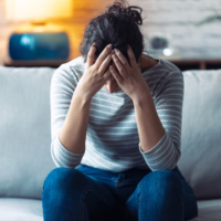 Shot of depressed young woman thinking about her problems while sitting on the sofa at home.